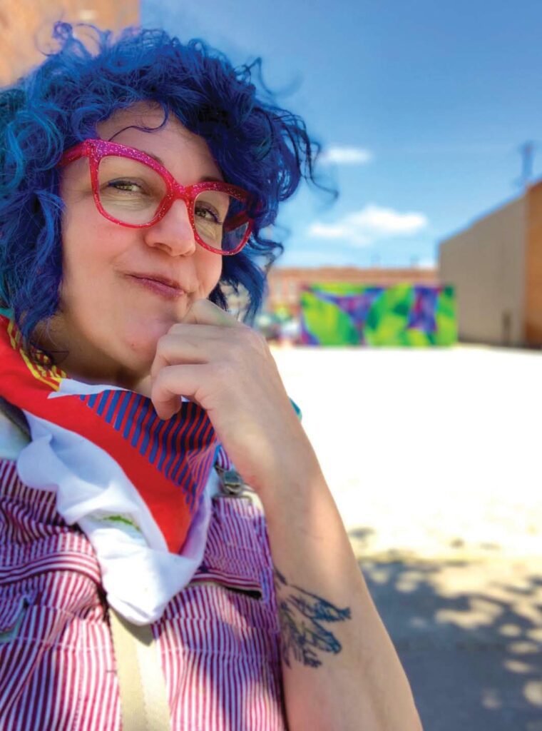 Sarah Johnson poses for a selfie with a mural she painted on a shipping container in the background